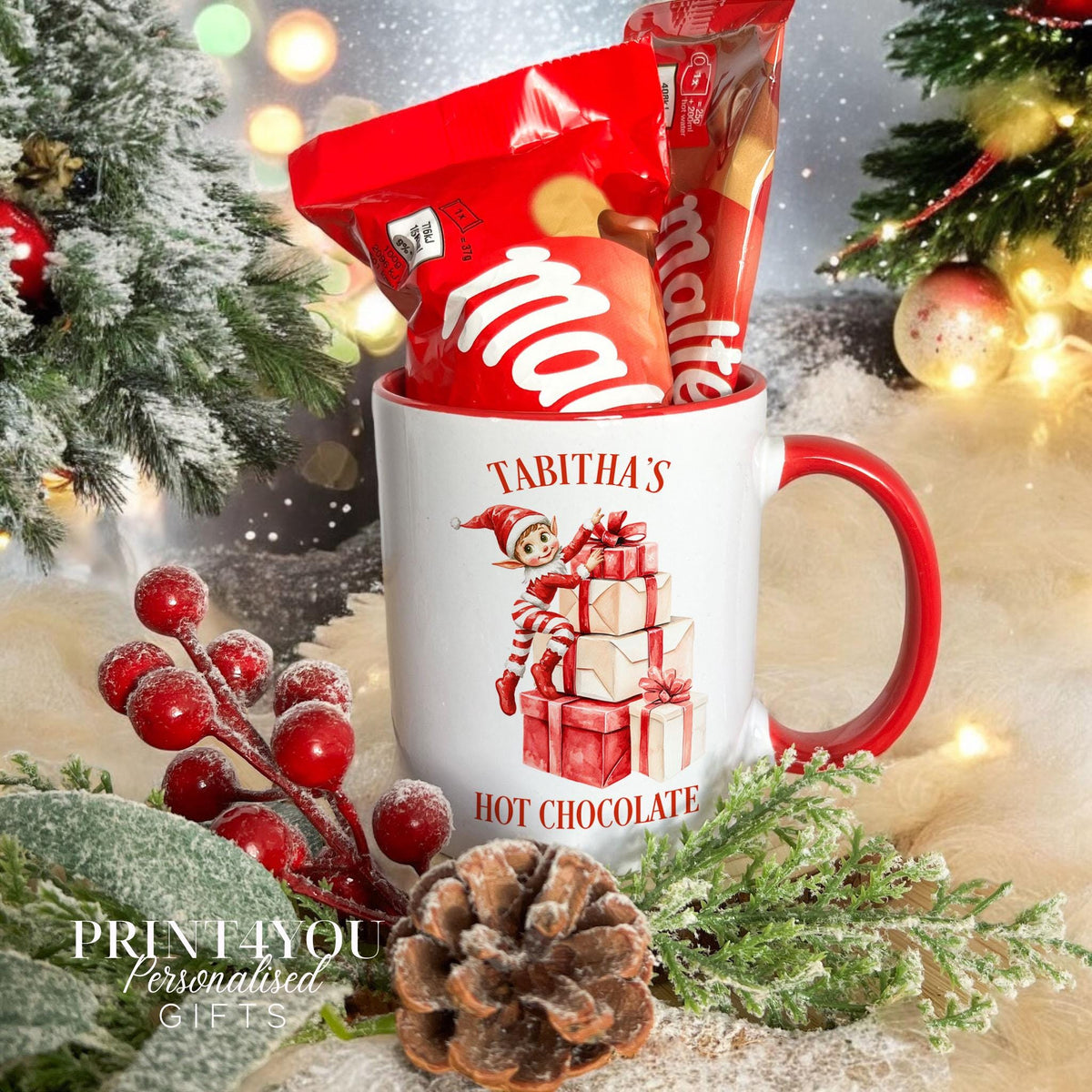 Personalised Christmas mug with a red handle, printed with an elf sitting on a stack of presents and the name Tabitha, shown with the optional Maltesers hot chocolate gift set