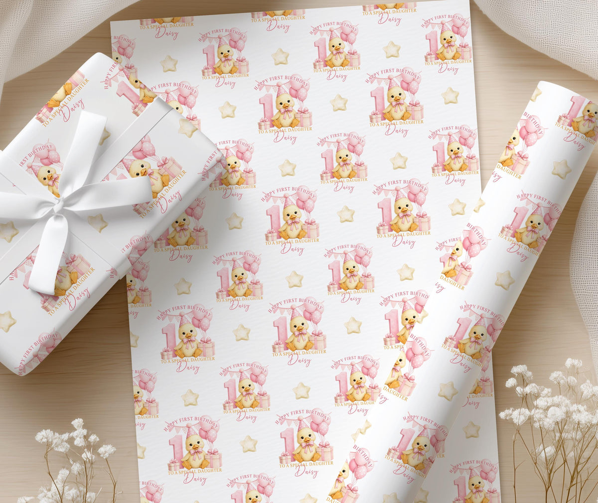 Personalised first birthday wrapping paper displayed flat, featuring a repeating duckling, pink number one, balloons and gift design on premium white paper.