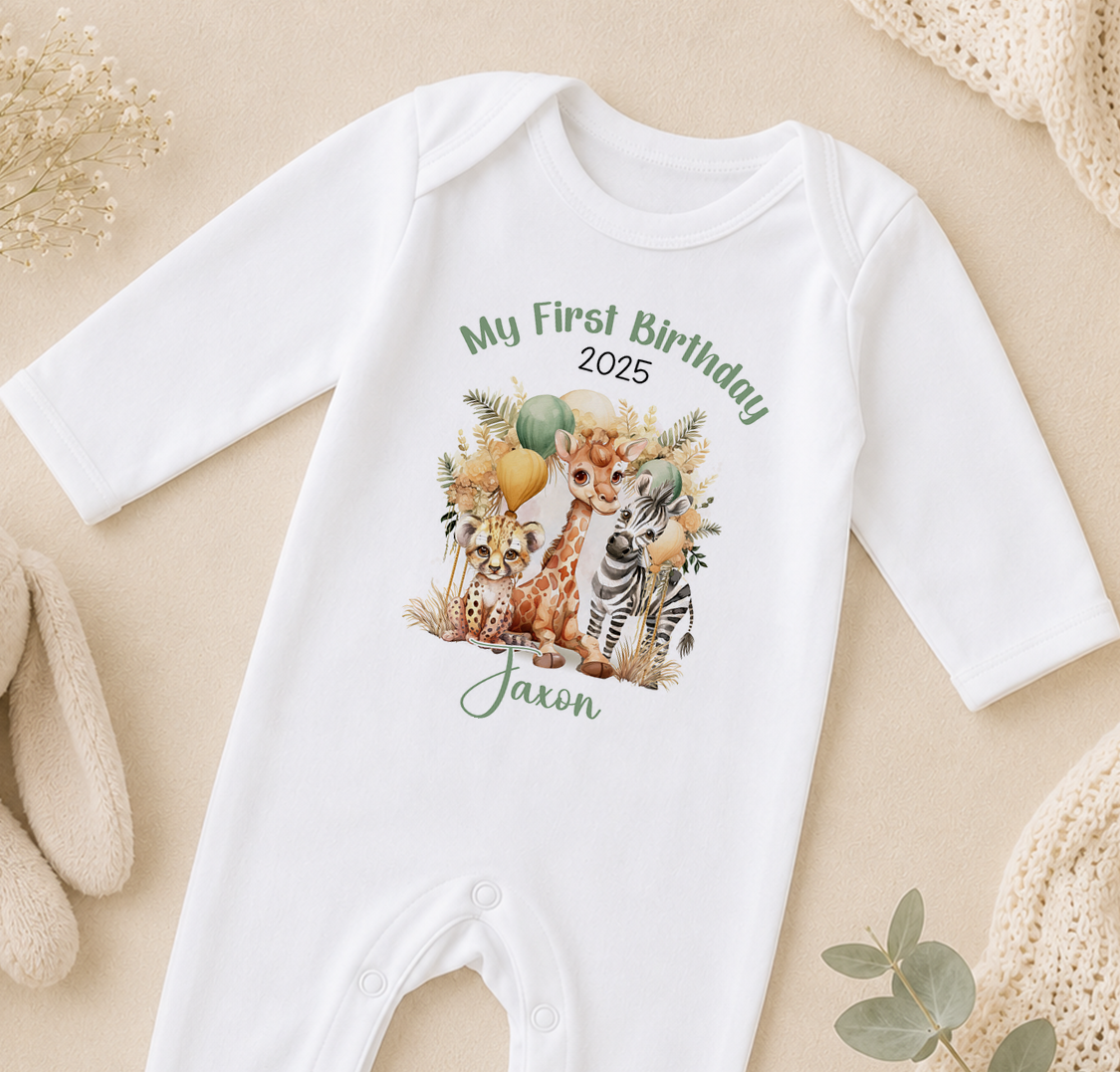 A white onesie with a printed image of a giraffe, zebra, and other animals, along with the text "My First Birthday" and "Jaxon" printed on it.