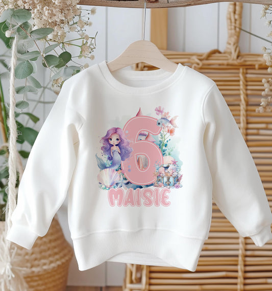 White cotton sweatshirt printed with a personalised mermaid design, name and birthday number.