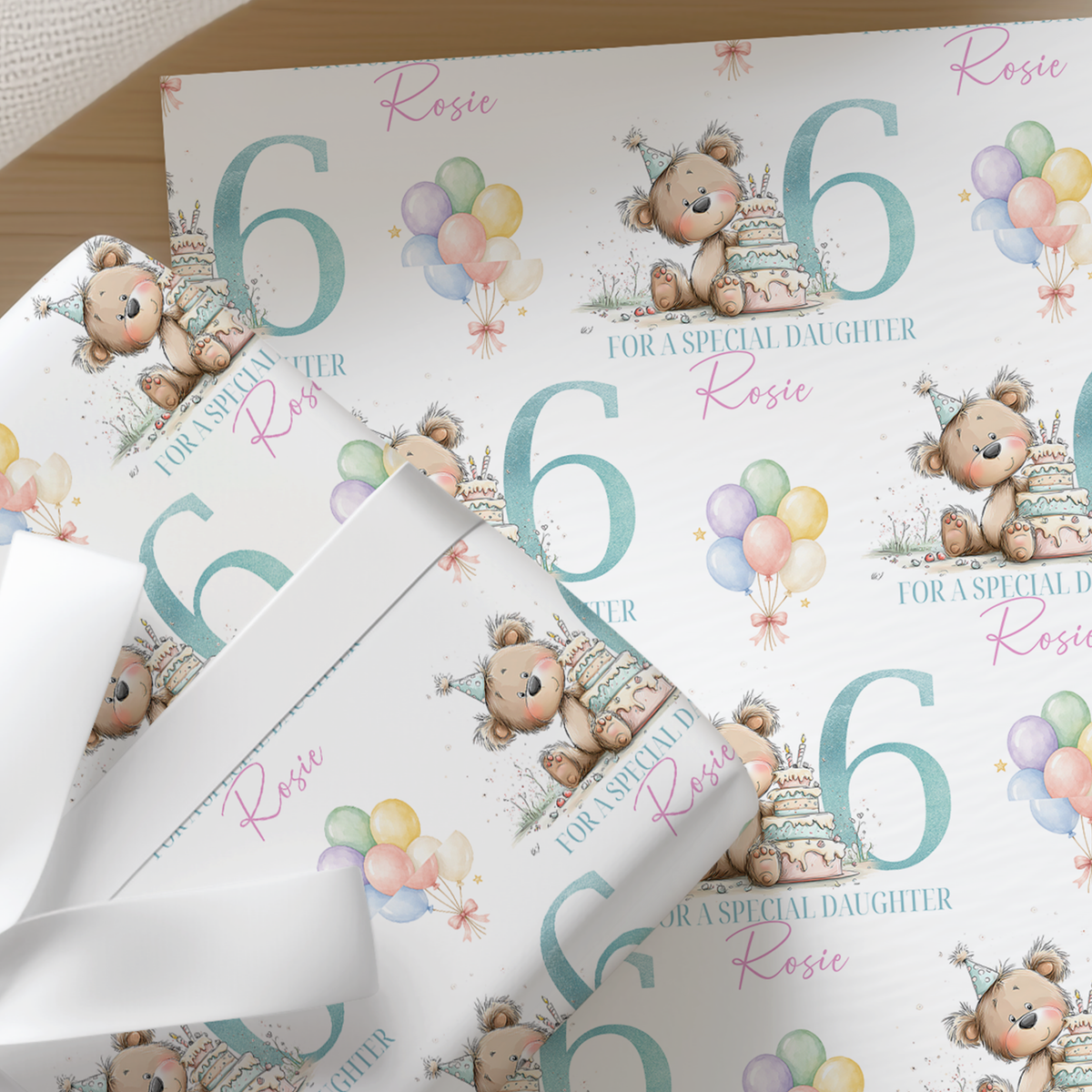 Repeating pattern of teddy bears and balloons on personalised birthday wrapping paper, shown with an example name, age six and 'for a special daughter' text