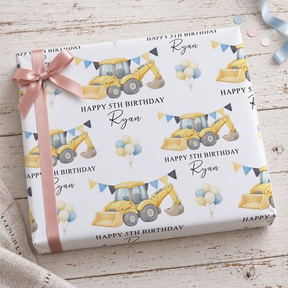 The image is a birthday gift wrapped with a pattern featuring construction vehicles and balloons, with the name "Ryan" written on it.