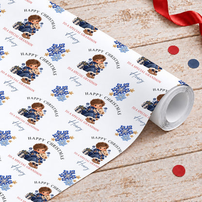 Roll of personalised grandson Christmas wrapping paper with a boy hugging a teddy bear, blue snowflakes and gold stars