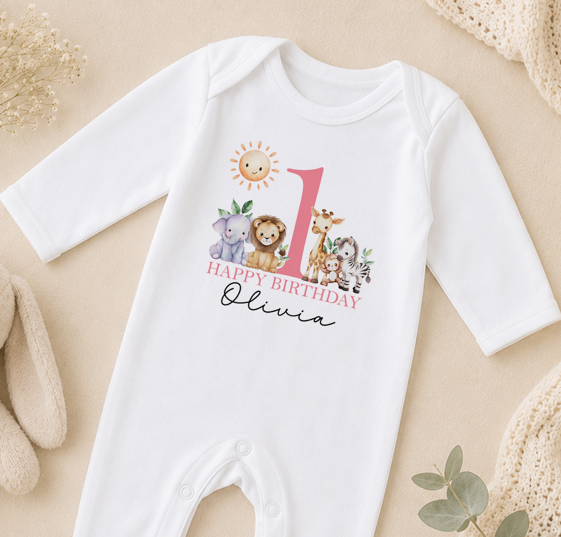 A white onesie with a printed design of various animals, including a sun, giraffe, lion, and elephant, along with the text "Happy Birthday Olivia".