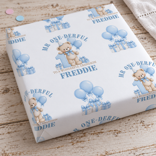 a white gift box with a repeating pattern of blue balloons and teddy bears, along with the text "Mr. One-Derrful to a Wonderful Grandson" printed on it.