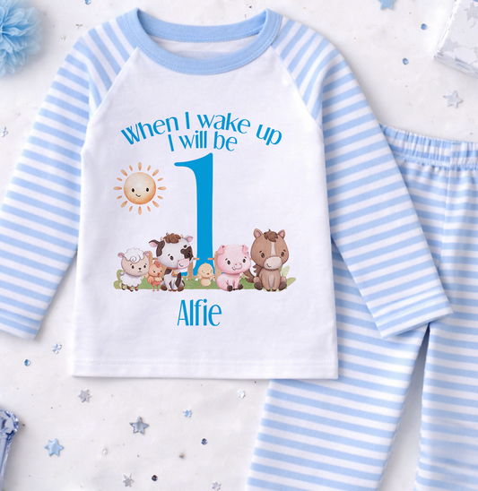 A white and blue striped onesie with a cartoon image of farm animals and the text "When I wake up I will be 1" printed on it, along with the name "Alfie".