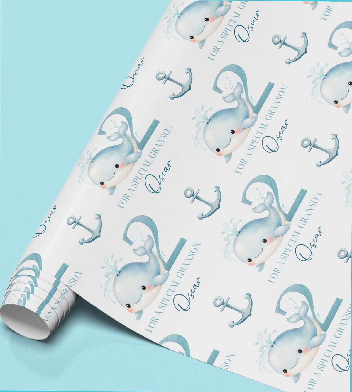 Roll of personalised boys' wrapping paper featuring a repeating pastel blue whale and anchor design.