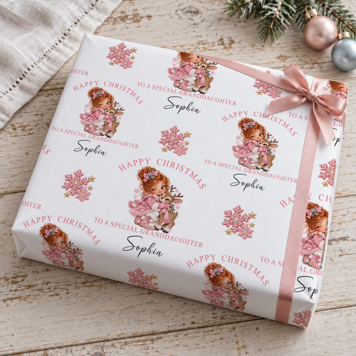Gift wrapped in personalised girl and reindeer Christmas wrapping paper tied with a pink satin bow