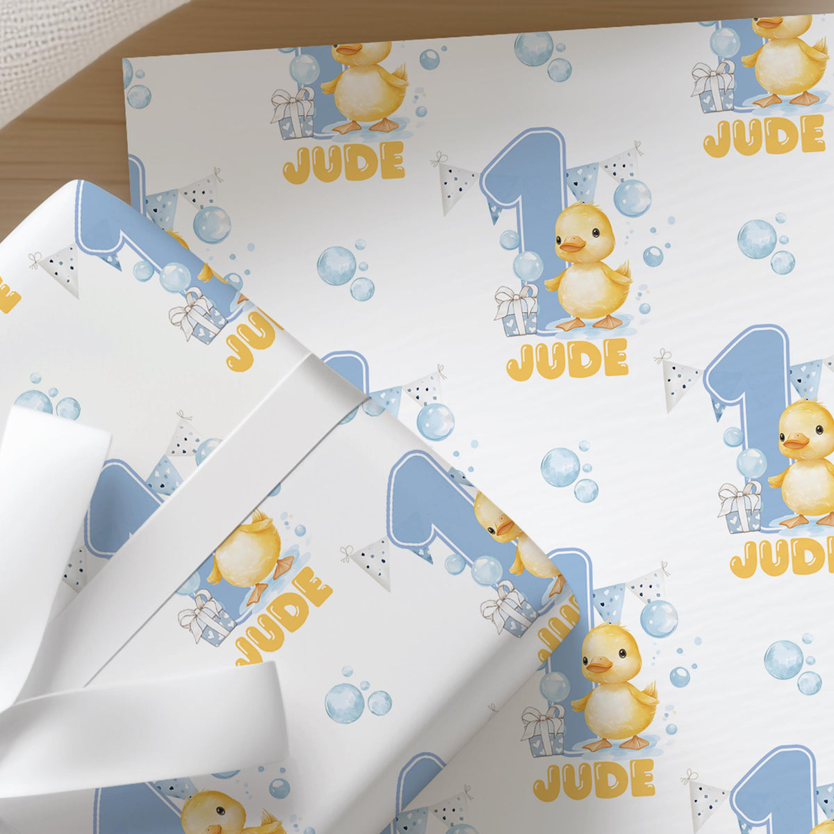 Close-up of blue and white duck wrapping paper pattern personalised with the name Jude.