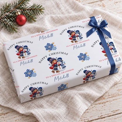 Gift wrapped in personalised grandson snowman Christmas wrapping paper with a navy bow on a linen cloth