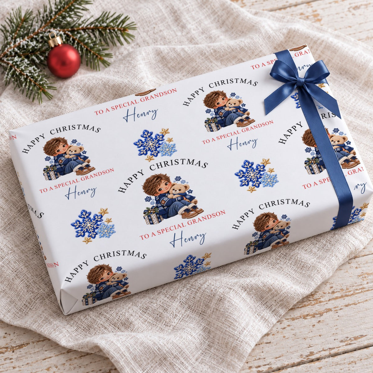 Gift wrapped in personalised grandson Christmas wrapping paper with a navy bow on a linen cloth