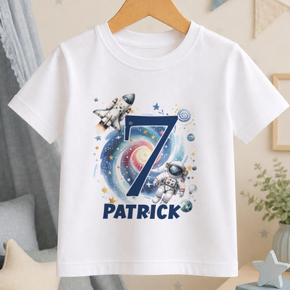 Personalised space birthday t-shirt – white tee with a navy number 7 over a galaxy with a rocket and astronaut, and the name Patrick