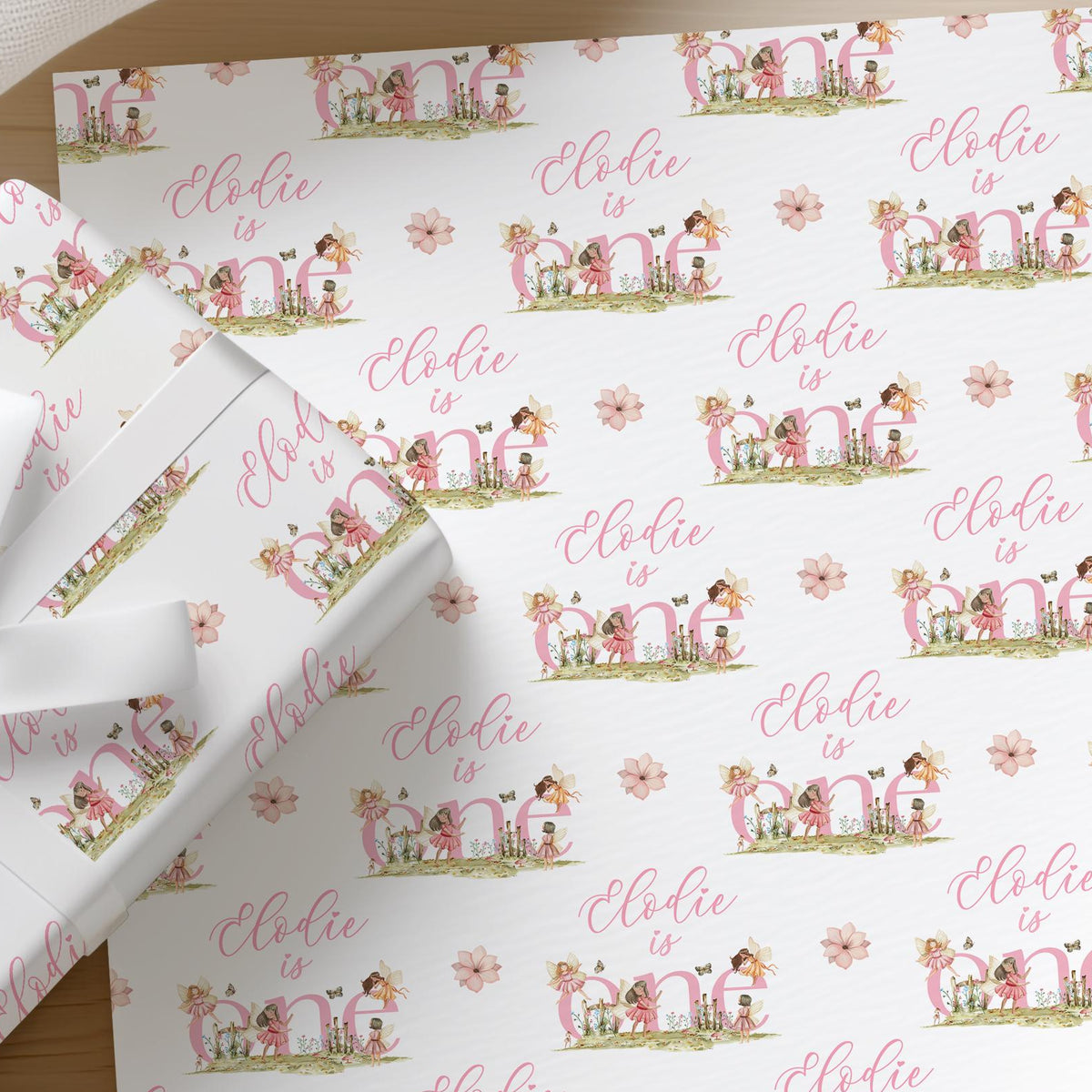 Roll of personalised pink fairy wrapping paper with an example name printed across the floral design