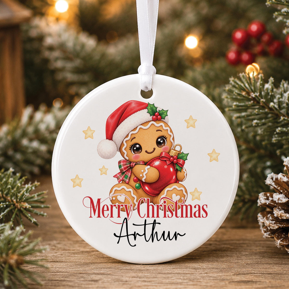 Personalised white ceramic Christmas bauble with a gingerbread man in a Santa hat, “Merry Christmas” and a name, hanging on a tree