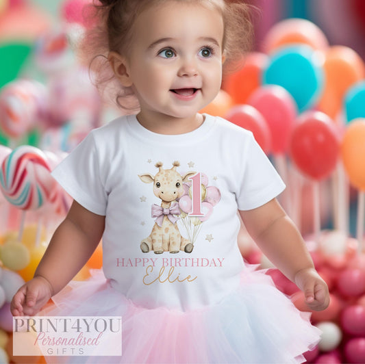 a one year old toddler wearing a white t-shirt printed with a cute giraffe holding pink and gold balloons. There is text reading Happy Birthday and a name, and a large pink number one.