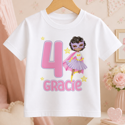 White cotton t-shirt printed with a superhero girl in an afro hairstyle, a large age number and personalised name