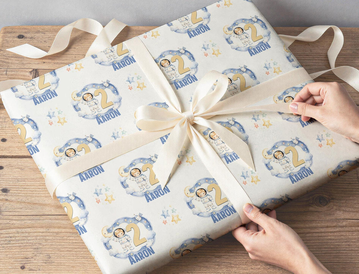 A wrapped gift box finished with ribbon, wrapped in the personalised moon and stars space wrapping paper