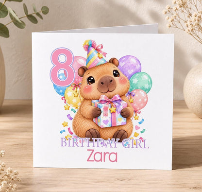 Personalised capybara birthday card – capybara hugging a pink present with balloons and a pink 8, Birthday Girl Zara