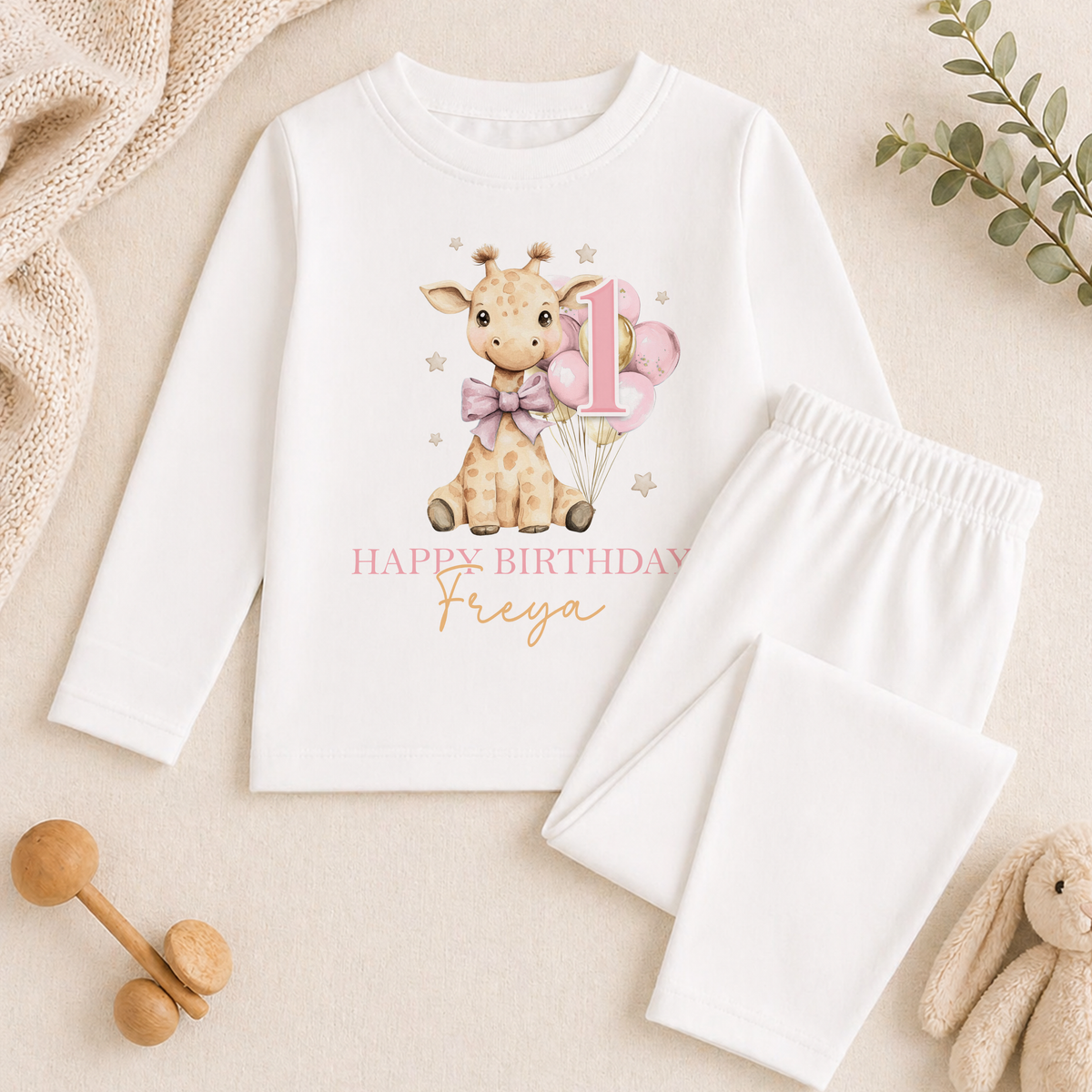A white long-sleeved shirt with a giraffe and the number 1 printed on it, along with a pair of white pajama pants. The shirt also has a "Happy Birthday Freya" message printed on it.