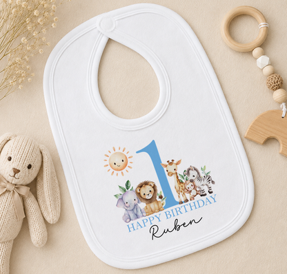 A white baby bib with a blue number 1 and a cartoon illustration of various animals, including a lion, giraffe, and zebra, along with the text "Happy Birthday Ruben".