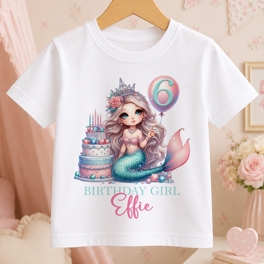 A white t-shirt with a mermaid graphic and a birthday cake, along with the text "Birthday Girl Elsie" printed on it.