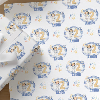 Close-up of the personalised moon and stars space wrapping paper featuring an astronaut, with a custom name and age, ideal for a boy's birthday