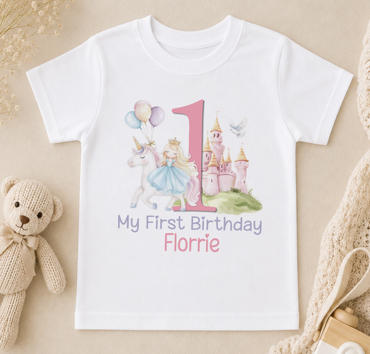 White children's t-shirt printed with a princess, castle and unicorn design and the personalised text 'My First Birthday Florrie'.