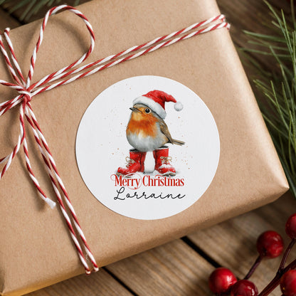 Personalised robin Christmas sticker in a Santa hat and red boots, stuck on a rustic gift box wrapped with twine and pine branches