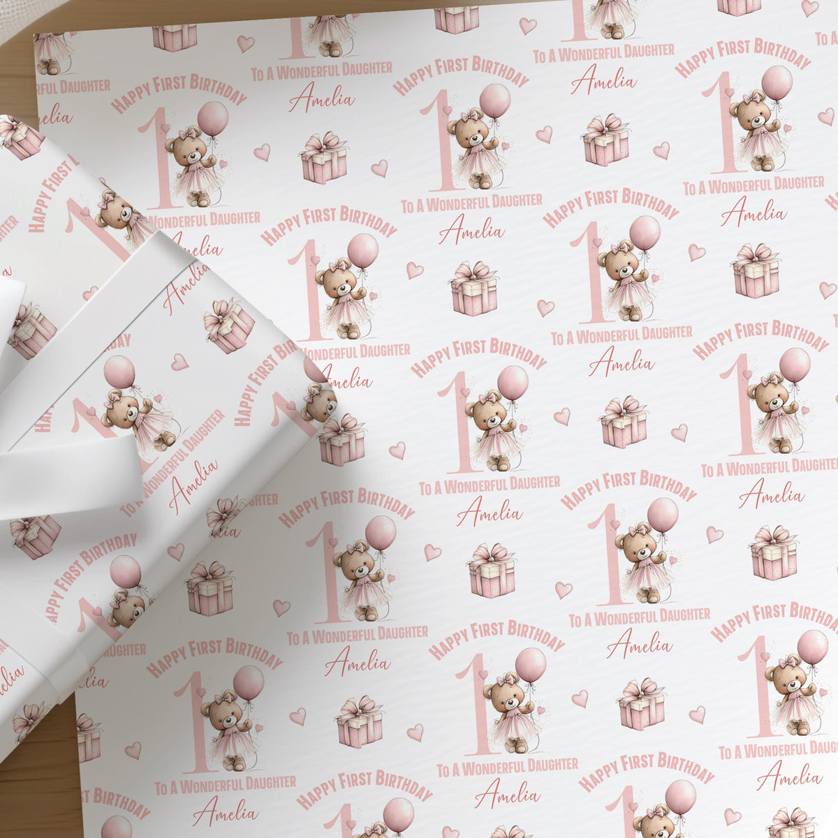 Close-up of the personalised pink ballerina teddy bear first birthday wrapping paper, showing the balloon, gift box and custom name detail.