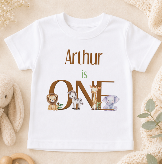 A white t-shirt with the text "Arthur is ONE" printed on it, surrounded by illustrations of various animals.