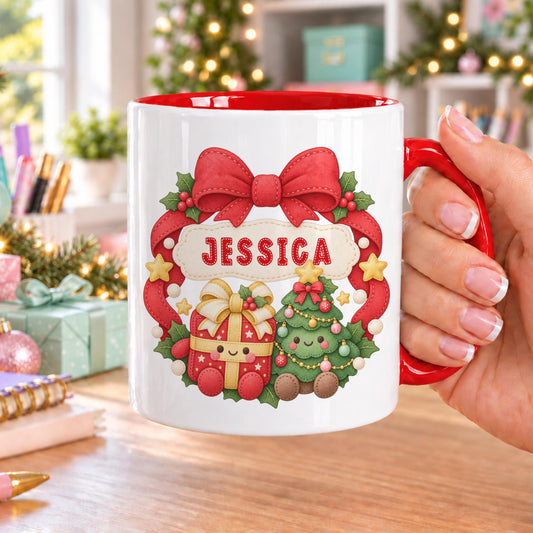 Personalised Christmas mug with red handle and inside, printed with a red wreath and bow, a smiling present and Christmas tree, and a name on a banner at the top