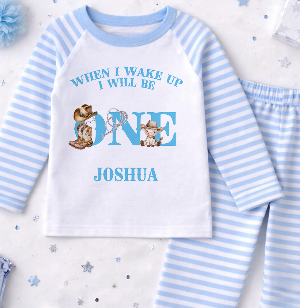 A white and blue pajama set with a personalized text and cartoon character design, along with some confetti and a blue flower.
