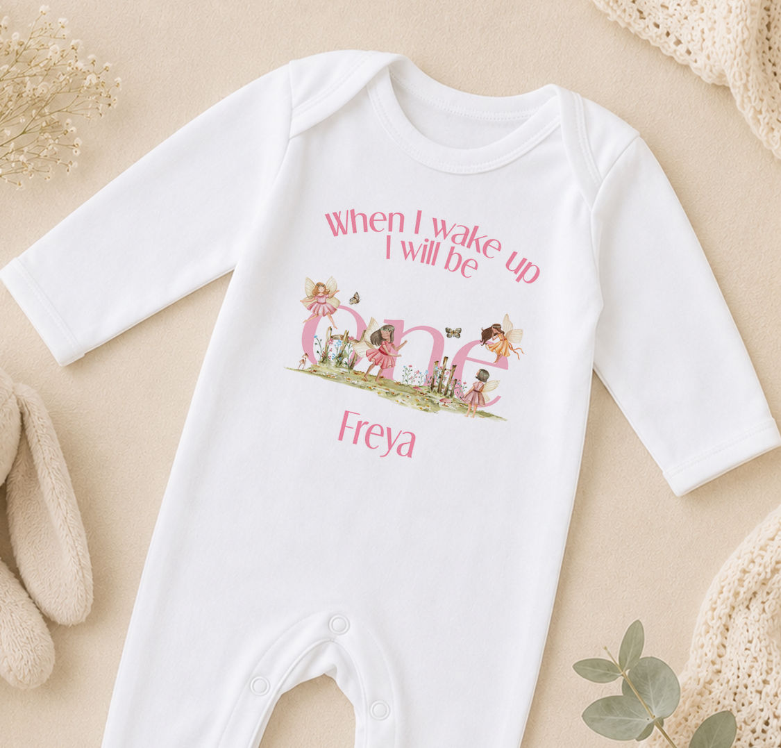 A white onesie with a personalized text and illustrations on it, placed on a beige surface.