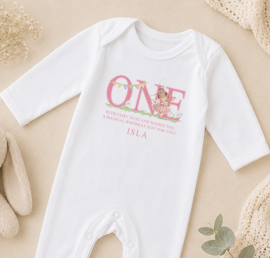 White baby onesie printed with a pink fairy first birthday design and a personalised message.