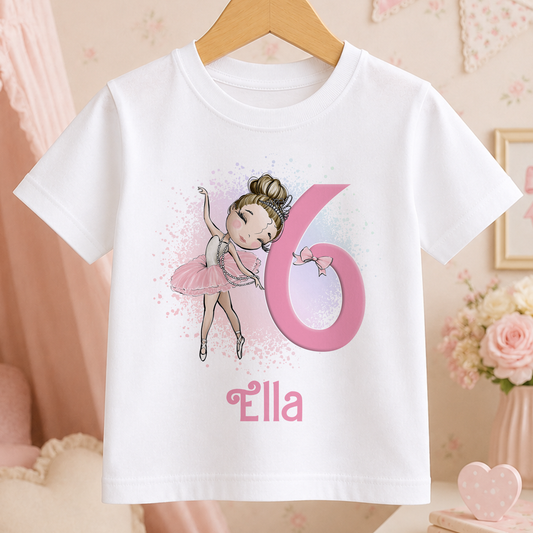A white t-shirt with a cartoon image of a young girl in a tutu and ballet pose, along with the number 6 and the name "ella" printed on it.