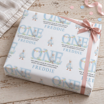a gift box with a pink ribbon and confetti on a wooden surface.