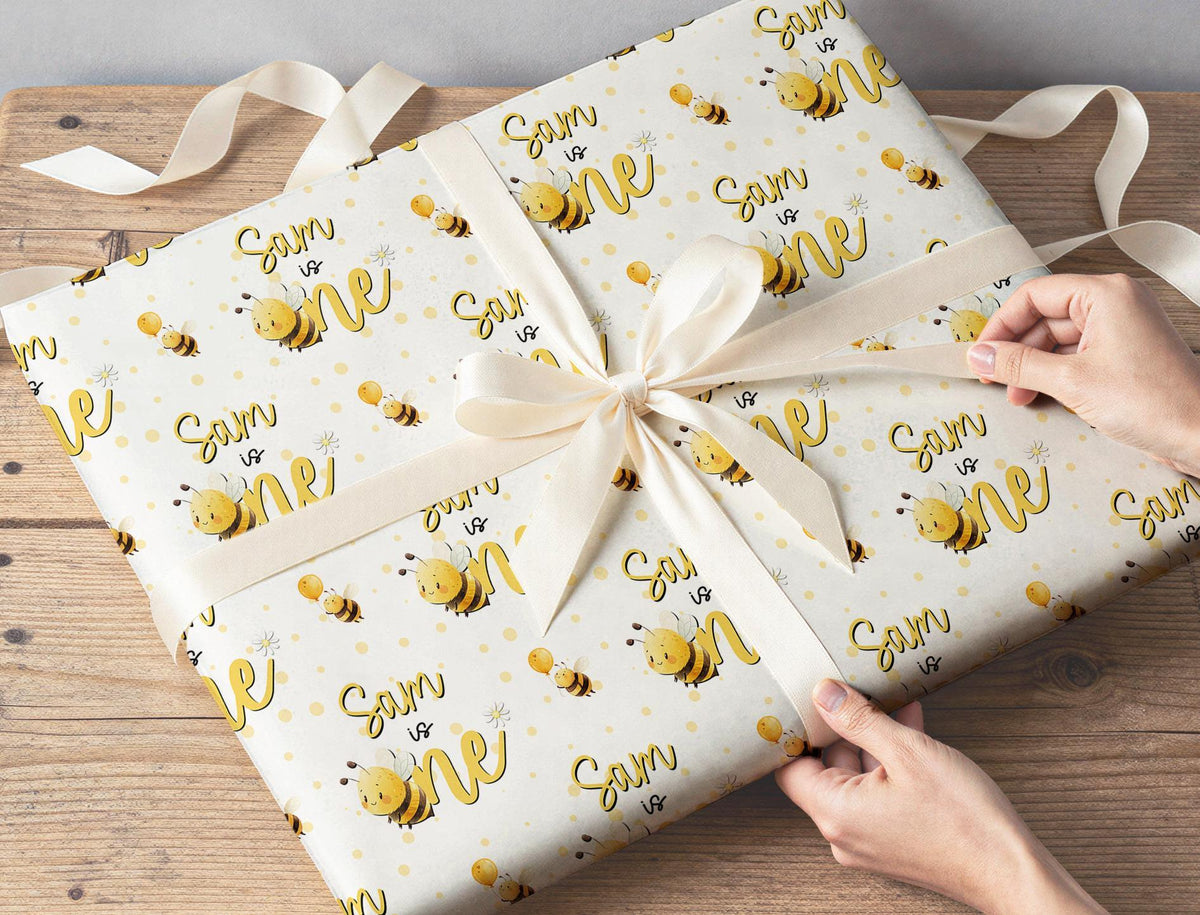 Personalised bee first birthday wrapping paper wrapped around a gift box
