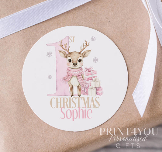 Glossy white round Christmas sticker personalised with a name, printed with a bright pink reindeer design, shown on a strip of stickers