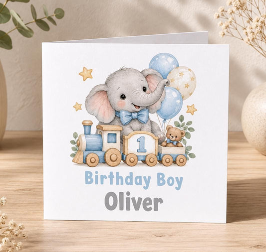Personalised elephant train 1st birthday card – grey elephant on a toy train with a number 1, blue balloons and Birthday Boy Oliver