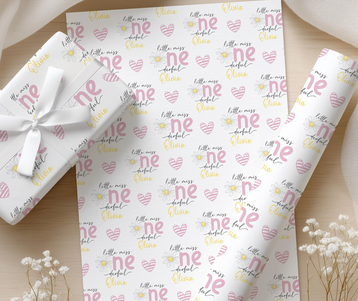 Close-up of the soft yellow daisy flower pattern and pink 'little miss' lettering printed on the wrapping paper