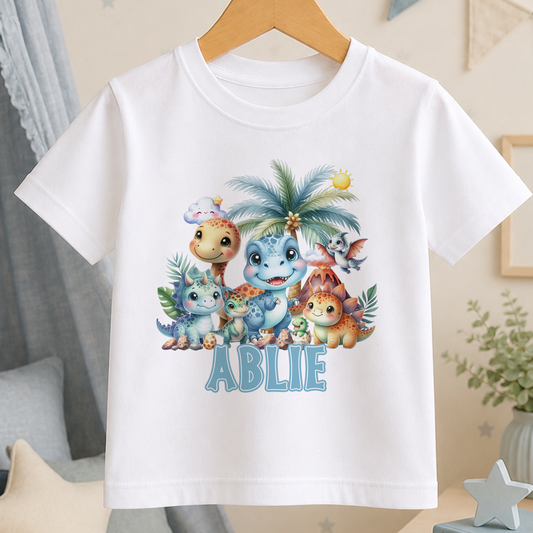 White t-shirt printed with a colourful dinosaur birthday design featuring cartoon dinosaurs and other animals, personalised with a name and age