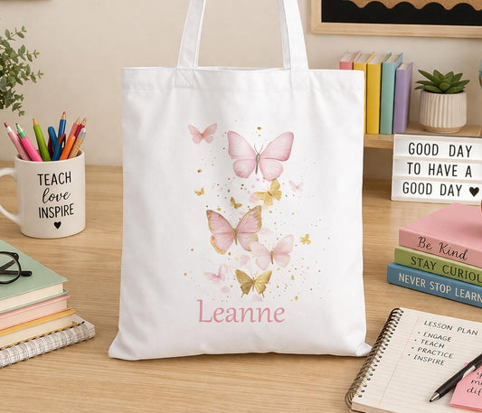 Cream cotton canvas tote bag printed with a soft, delicate butterfly design and personalised with a custom name, shown with shoulder straps
