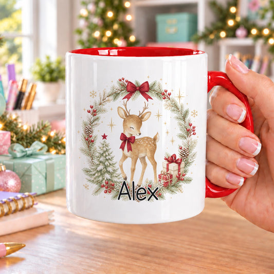 Personalised Christmas mug with red handle and inside, showing a watercolour reindeer with a red bow in a festive wreath with a tree and presents, and a name below