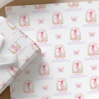 Flat lay of personalised floral pink butterfly wrapping paper for a girl's first birthday with a name printed across the sheet