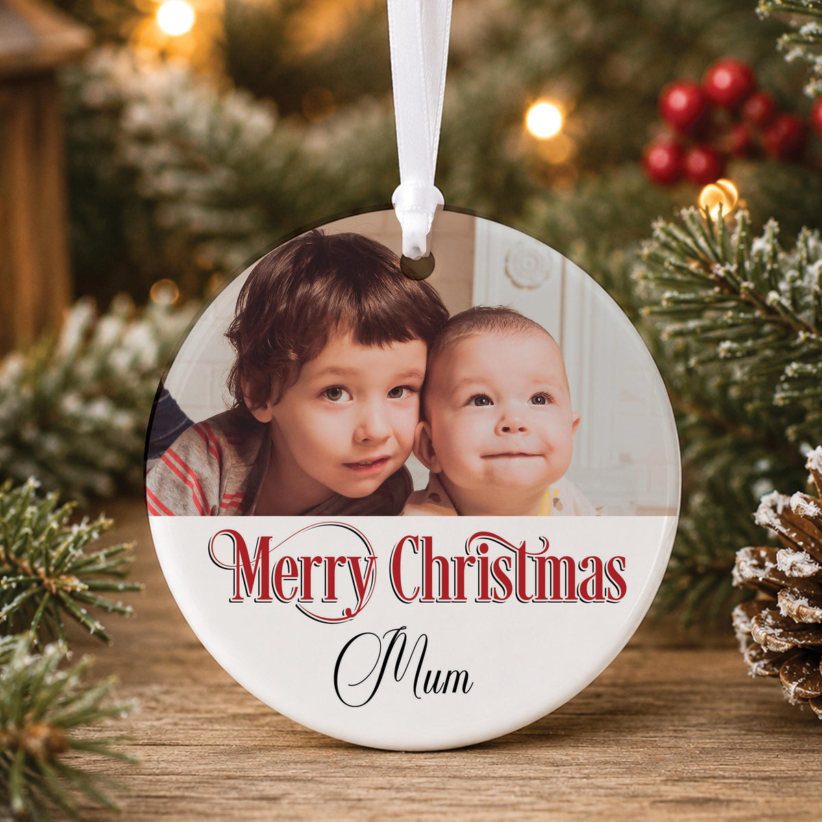 Personalised white ceramic Christmas photo bauble printed with a family photo, “Merry Christmas” and a name, hanging on a tree
