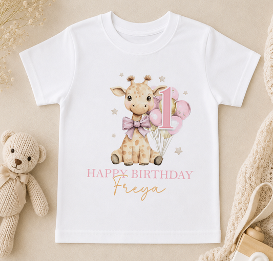 Personalised white t-shirt printed with a baby giraffe, pink and gold balloons and 'Happy Birthday Freya'.