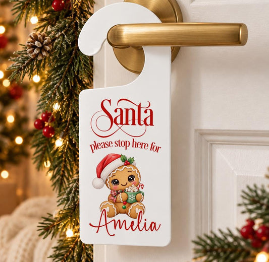 Personalised Santa please stop here door hanger with a gingerbread man in a Santa hat and child’s name in red, hanging on a door handle