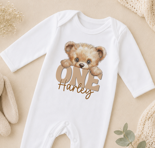 White baby onesie printed with a teddy bear design and the personalised text 'ONE Harley'.
