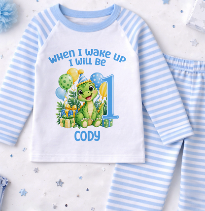 Personalised blue and white striped first birthday pyjamas printed When I Wake Up I Will Be 1 with a green dinosaur, balloons and the name Cody
