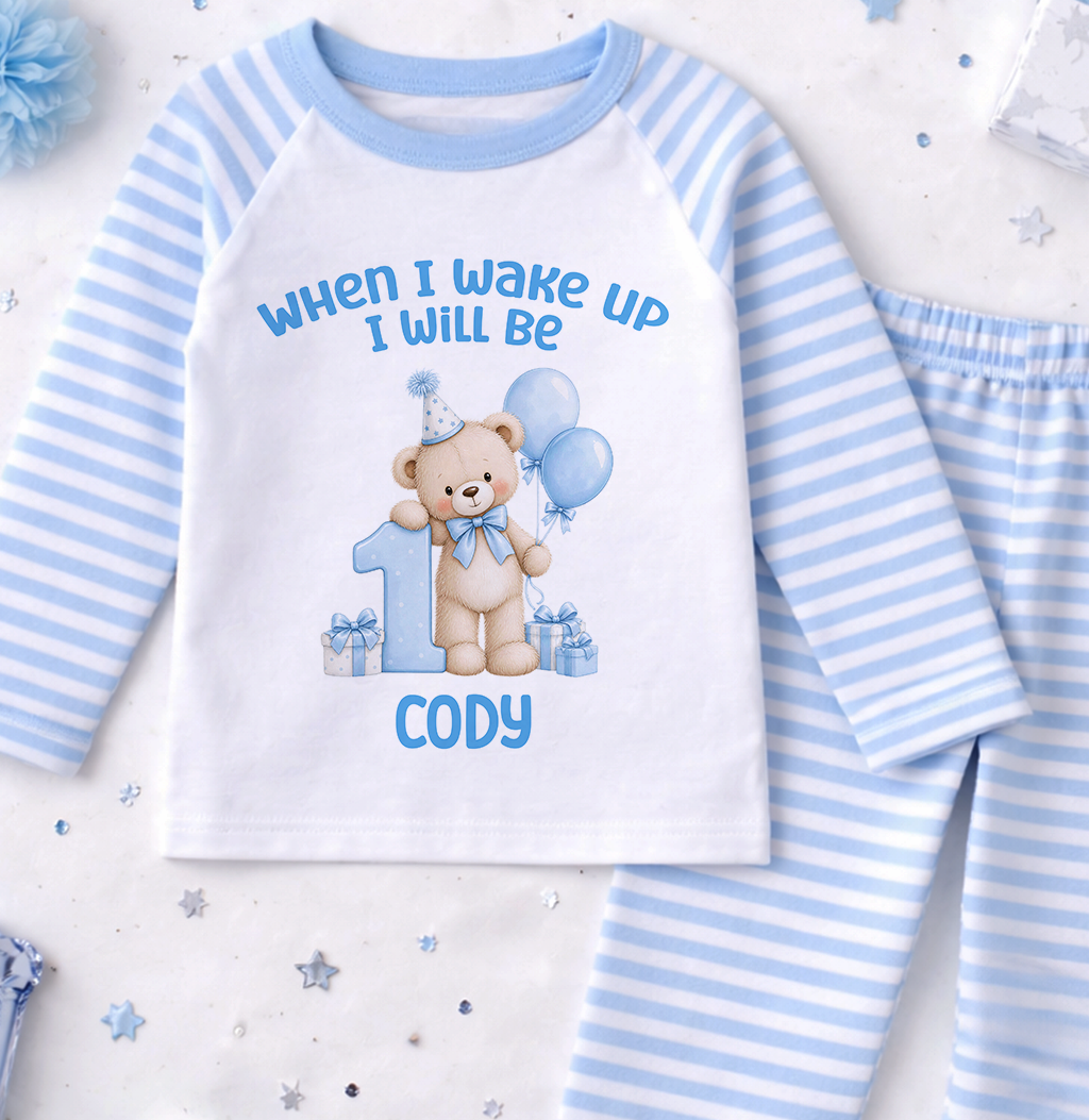 Personalised blue and white striped first birthday pyjamas printed When I Wake Up I Will Be 1 with a teddy bear, balloons and the name Cody